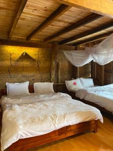una camera con due letti in una stanza con soffitti in legno di Homestay Chu Vang a Phong Thổ
