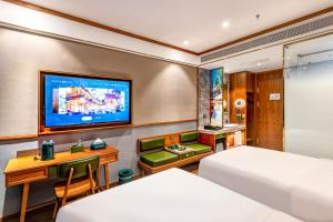 a hotel room with a bed and a desk and a tv at Nostalgia S Hotel - North Railway Station Kunming in Kunming
