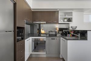 uma cozinha com electrodomésticos de aço inoxidável e armários castanhos em Private 2-Bed Apartment & 5 minutes walk to QPAC em Brisbane