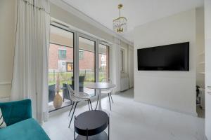 sala de estar con TV, mesa y sillas en Sunny Garden by Grand Apartments en Gdansk