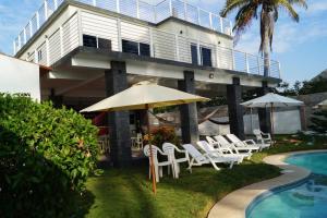 un edificio con sillas, sombrilla y piscina en Casa BLUE paradise HOUSE, en El Corozal