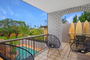 a balcony with two chairs and a table and surfboards at Paradise Villas - Villa 2 in Gold Coast