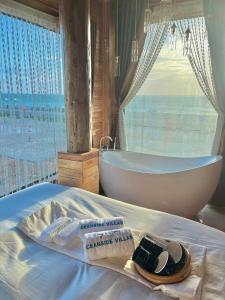 ein Bad mit einer Badewanne, einem Waschbecken und einem Bett in der Unterkunft Oceanside Villa Phuquy Island in Cu Lao Thu