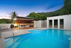a swimming pool in front of a house at The Orchard House - Luxury Tropical Villa in Redlynch