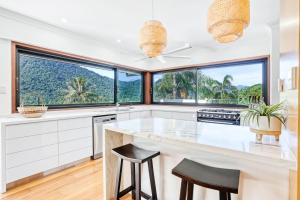 a kitchen with white cabinets and large windows at The Orchard House - Luxury Tropical Villa in Redlynch