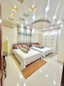 Duas camas num quarto com paredes brancas em Cherry Homestay - Hoàng Đế motel em Chau Doc