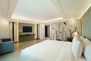 a bedroom with a large white bed and a television at Tavia Heritage Hotel in Jakarta