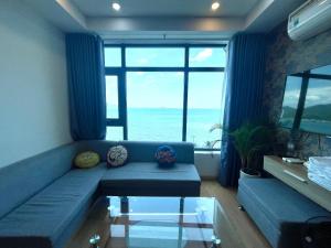 - un salon avec un canapé bleu offrant une vue sur l'océan dans l'établissement Nha Trang Ocean View Apartment, à Nha Trang