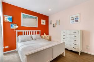 een slaapkamer met een wit bed en een oranje muur bij Quirky, Spacious & Sophisticated 2-Bed in St Kilda in Melbourne