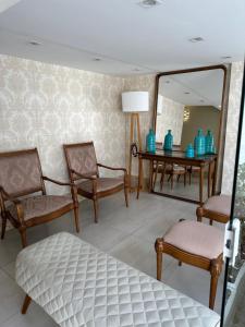 een kamer met stoelen, een spiegel en een tafel bij Apartamento no centro de Juiz de Fora in Juiz de Fora