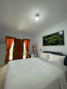 a bedroom with a large white bed with orange curtains at Canggu 77 Guest House in Canggu
