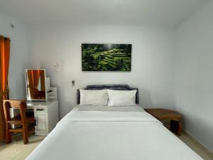 a bedroom with a white bed and a desk at Canggu 77 Guest House in Canggu