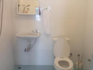 a white bathroom with a toilet and a sink at Happy Home Guest House in Ban Phe