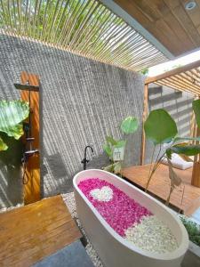 a bath tub filled with pink flowers on a patio at Akaya Villas Solo in Kemiri