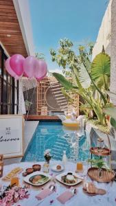 a table with plates of food next to a swimming pool at Akaya Villas Solo in Kemiri