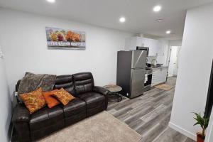 a living room with a leather couch and a kitchen at New Decently Furnished Suit in Regina