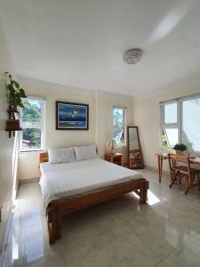 a bedroom with a bed and a table and windows at 2Stones Cát Bà Homestay in Cat Ba
