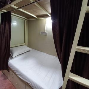 a small bedroom with a bed and a ladder at New Assar International dormitory in Mumbai