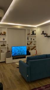 a living room with a blue couch and a flat screen tv at Joli Duplex in Amilcar