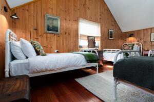 a bedroom with a white bed and wooden walls at Rustic Barn by the Bay in Low Head