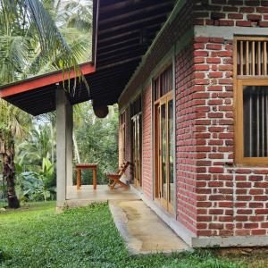ein Backsteingebäude mit einer Veranda und einer Bank daneben in der Unterkunft THE HIDEOUT KURUNEGALA in Kurunegala