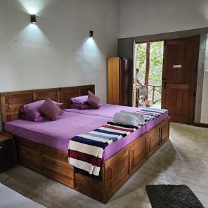 Un dormitorio con una gran cama de madera con sábanas moradas. en THE HIDEOUT KURUNEGALA en Kurunegala