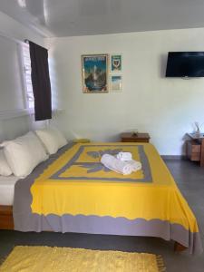 a bedroom with a bed with a yellow blanket at Bungalow APETAHI in Faaa