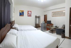 a bedroom with two beds and a desk and a television at Yan Gui Lai B&B in Hengchun
