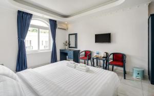 1 Schlafzimmer mit einem weißen Bett und 2 roten Stühlen in der Unterkunft La Casona Boutique Hotel in Ho-Chi-Minh-Stadt