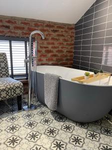 a bathroom with a bath tub and a chair at Town center cottage with Hot tub in Morpeth