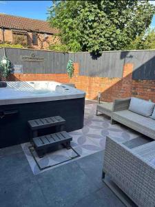 a patio with a tub and a couch and a bench at Town center cottage with Hot tub in Morpeth