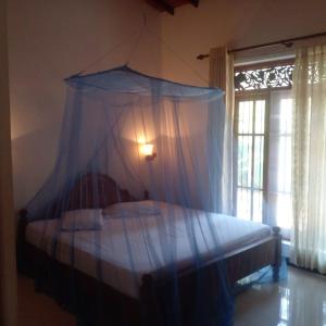 a bedroom with a canopy bed with a window at Paradise villa aluthgama in Aluthgama