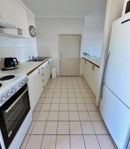a kitchen with white appliances and a white tiled floor at Mariners Cove at Paynesville in Paynesville