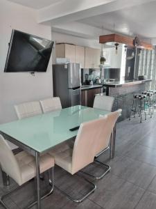 a kitchen with a glass table and white chairs at Santiago in Tacna