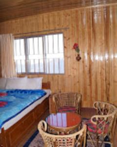 - une chambre avec un lit, une table et des chaises dans l'établissement HOTEL NIRALA , Darjeeling, à Darjeeling