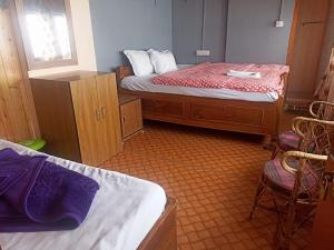 - une chambre avec 2 lits et 2 chaises dans l'établissement HOTEL NIRALA , Darjeeling, à Darjeeling