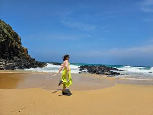 une femme en robe jaune marchant sur la plage dans l'établissement Homstay Lynh Lynh Phú Yên, à Liên Trì (3)