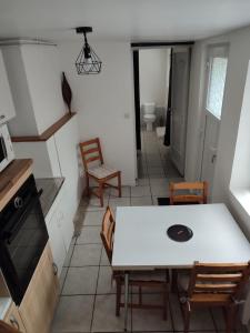 une salle à manger avec une table et des chaises blanches dans l'établissement Location petite maison, à Quillebeuf-sur-Seine