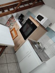 una pequeña cocina con fregadero y microondas en Location petite maison, en Quillebeuf-sur-Seine