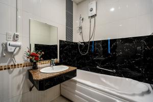 ein Badezimmer mit einem Waschbecken, einer Badewanne und einem Spiegel in der Unterkunft La Casona Boutique Hotel in Ho-Chi-Minh-Stadt