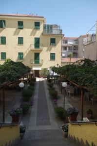 un bâtiment avec une cour ornée de plantes et d'arbres dans l'établissement Hotel Alba, à Lavagna