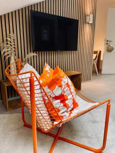 una silla naranja y blanca en una habitación con TV en Hotel-Bistro-Europa, en Merchweiler