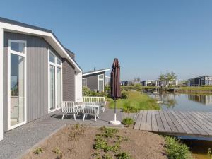 een patio met een parasol en een tafel en stoelen bij House with sauna at a holiday park in Zeeland in Wemeldinge