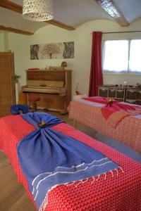 a bedroom with two beds and a piano at Gites de la Lurette - agréable T2 indépendant dans cadre calme et verdoyant in Cazilhac