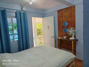 a bedroom with a bed with blue curtains and a window at Ani Marie Guest House in Coron