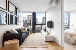 a living room with a couch and a bed at Luxuria Apartments - Collins House in Melbourne