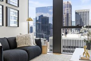 uma sala de estar com um sofá e uma grande janela em Luxuria Apartments - Collins House em Melbourne