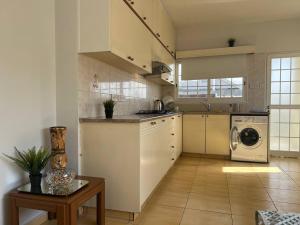 a kitchen with white cabinets and a washer and dryer at Quiet place in Limassol