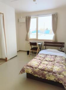 um quarto com uma cama, uma secretária e uma janela em ゲストハウス ikoi em Kyōgoku