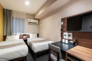 a hotel room with two beds and a desk at Hotel Sanrriott Osaka Hommachi in Osaka